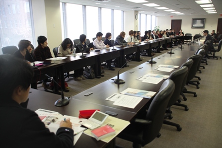 Wide view of meeting room. Students are listening.
